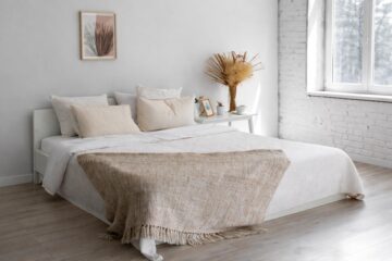 biała sypialnia z jasnym łóżkiem i naturalnymi dodatkami w spokojnej aranżacji