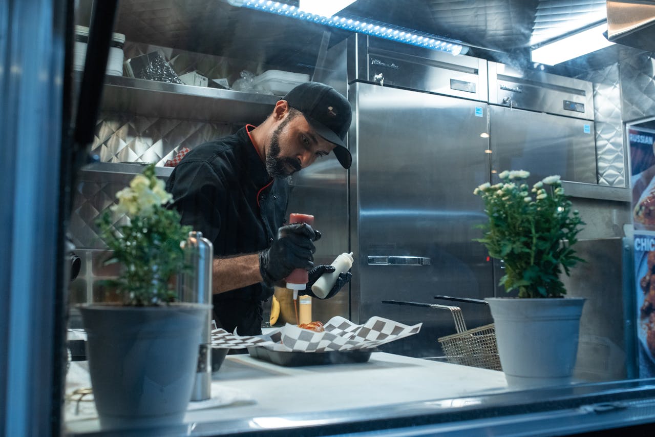 Kucharz przygotowujący danie street food w food trucku z egzotycznymi dodatkami